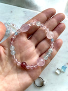 mixed gemstone bracelet held in hand with rose quartz focal bead aquamarine strawberry quartz and blue topaz accents, pastel crystal bracelet for heart chakra healing and calm