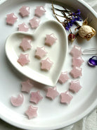 Small Rose Quartz star carvings on white. Celestial Heart Chakra stones for love, harmony, and intention-setting rituals.
