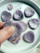 Lepidolite heart worry stone held in hand showing lilac purple crystal with white and gray inclusions