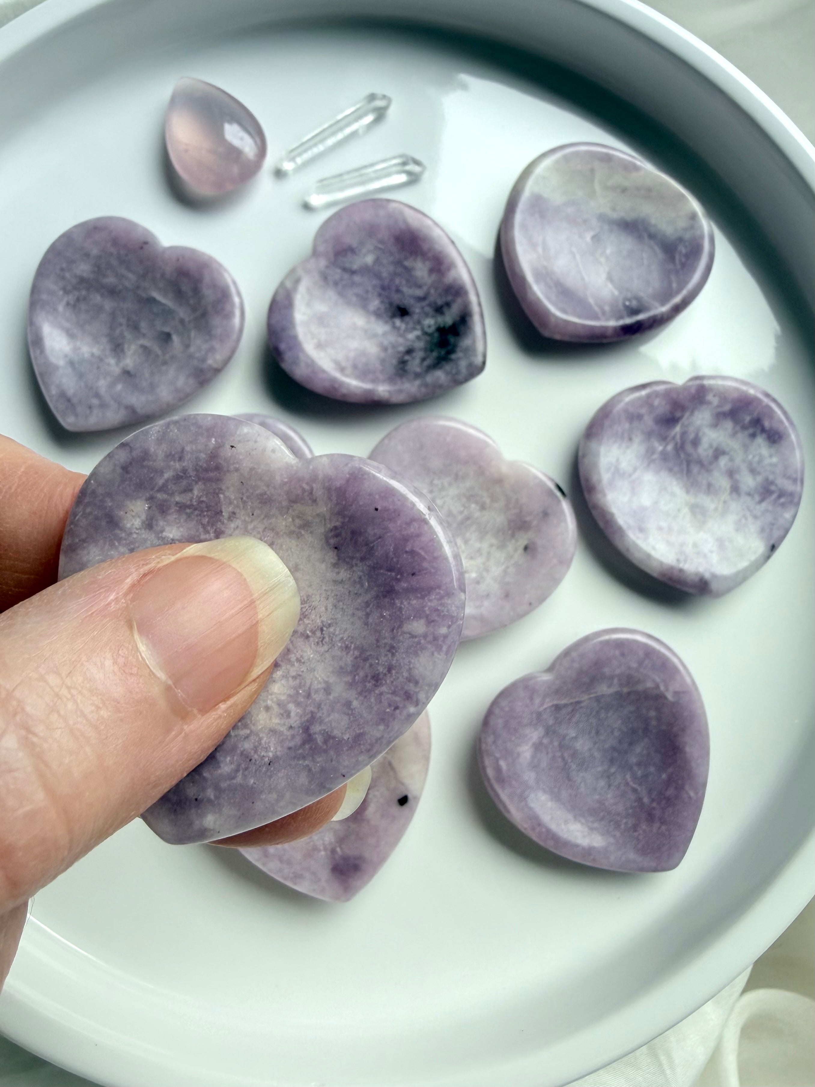 Lepidolite heart worry stone held in hand showing lilac purple crystal with white and gray inclusions