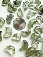 Green Tourmaline in Quartz moons with natural inclusions shown beside a coin for scale and size comparison