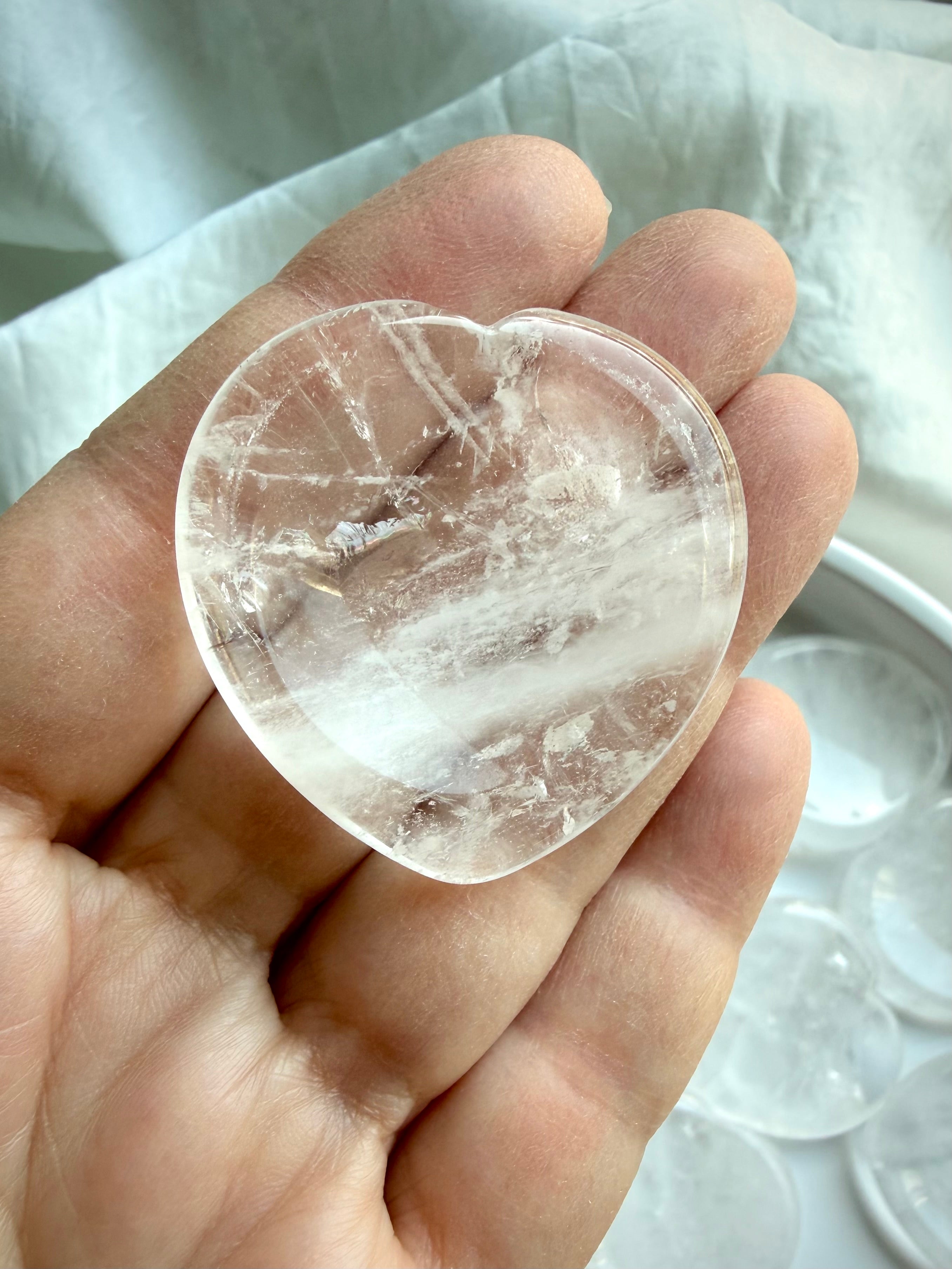 up close clear quartz heart stone held in hand for clarity focus and emotional balance