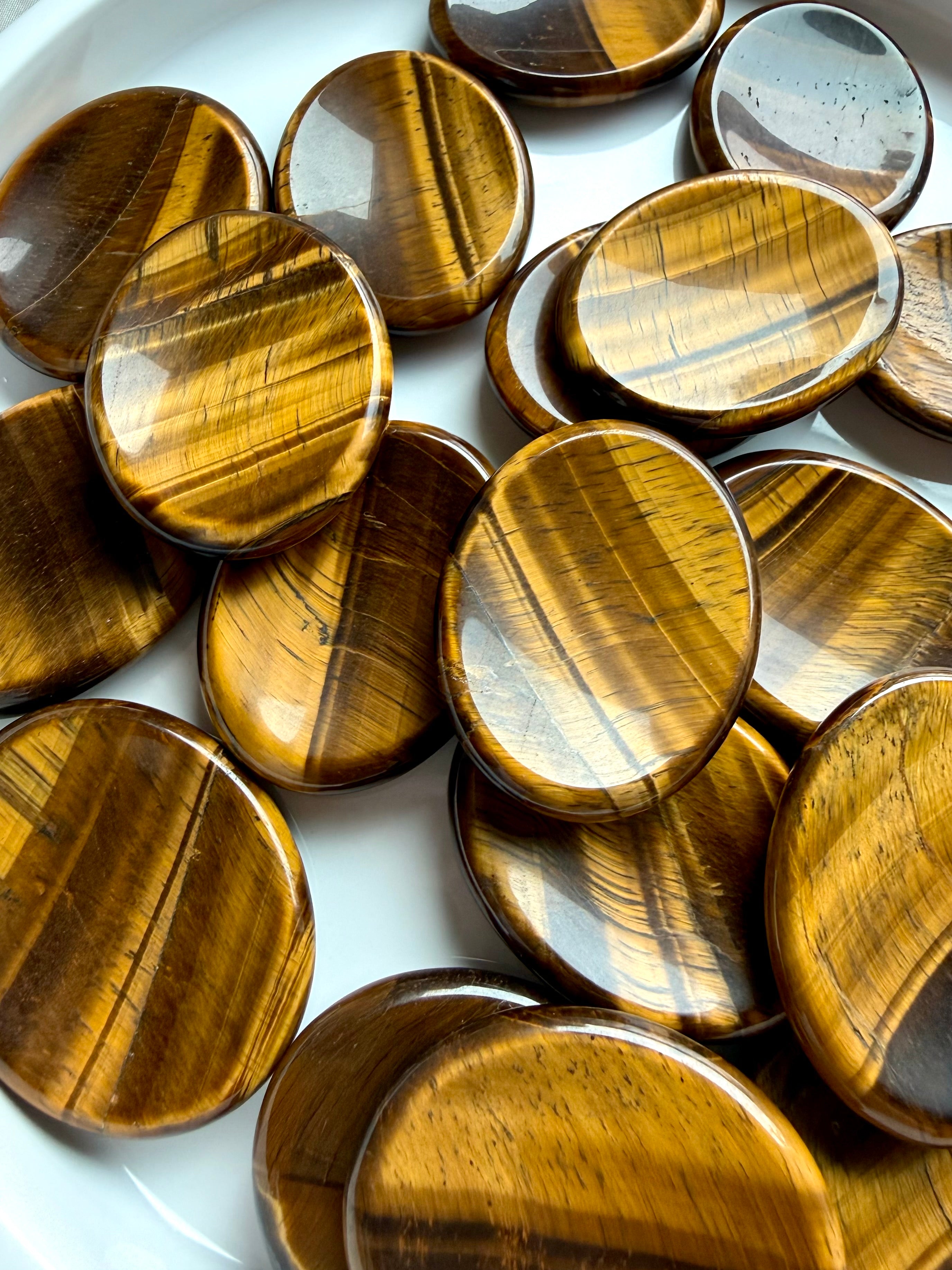 tiger’s eye worry stones oval thumb stones with golden chatoyancy on marble, grounding crystal for confidence protection and root chakra
