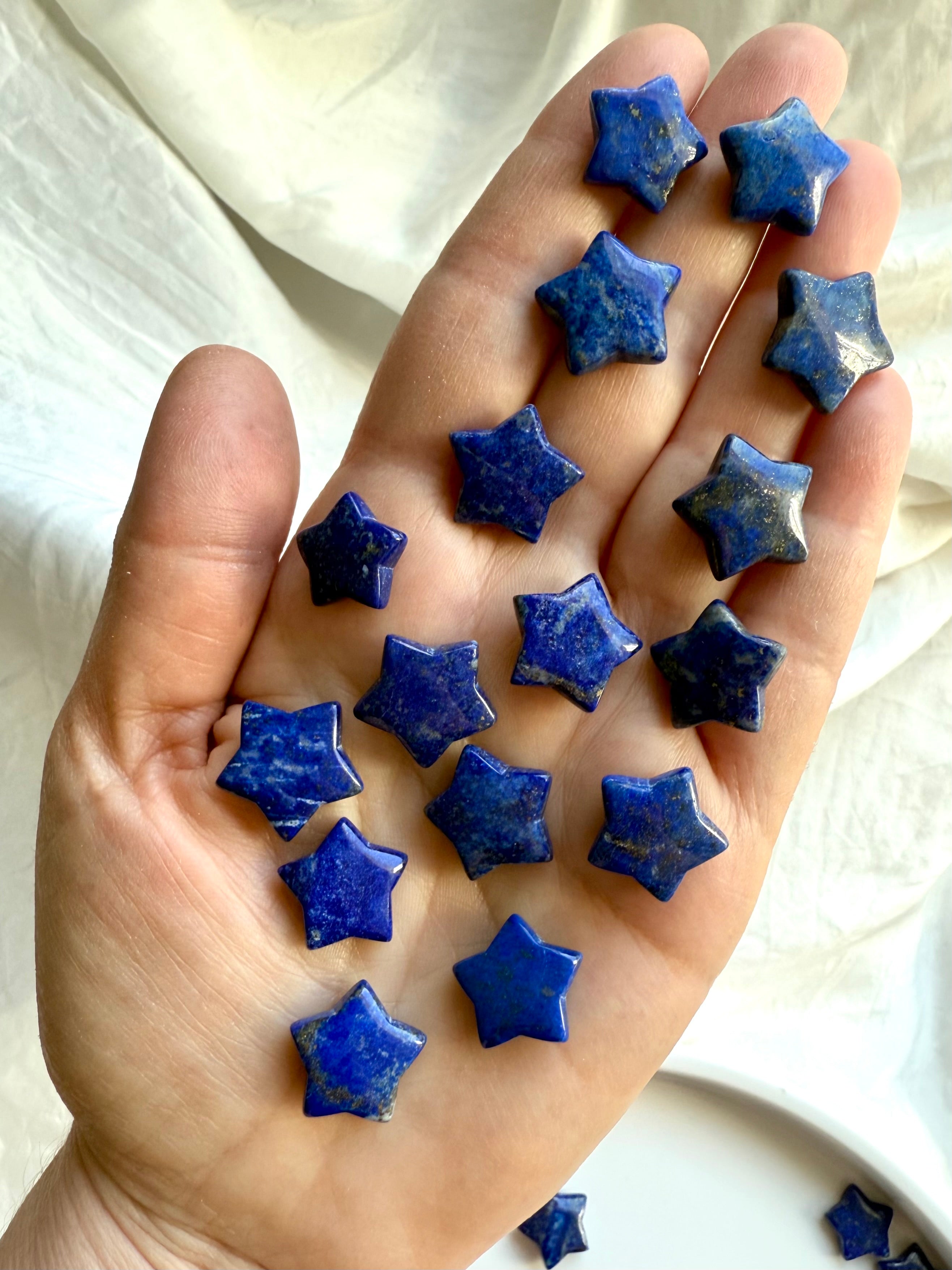 An array of blue Lapis Lazuli star crystals resting in open hand for scale