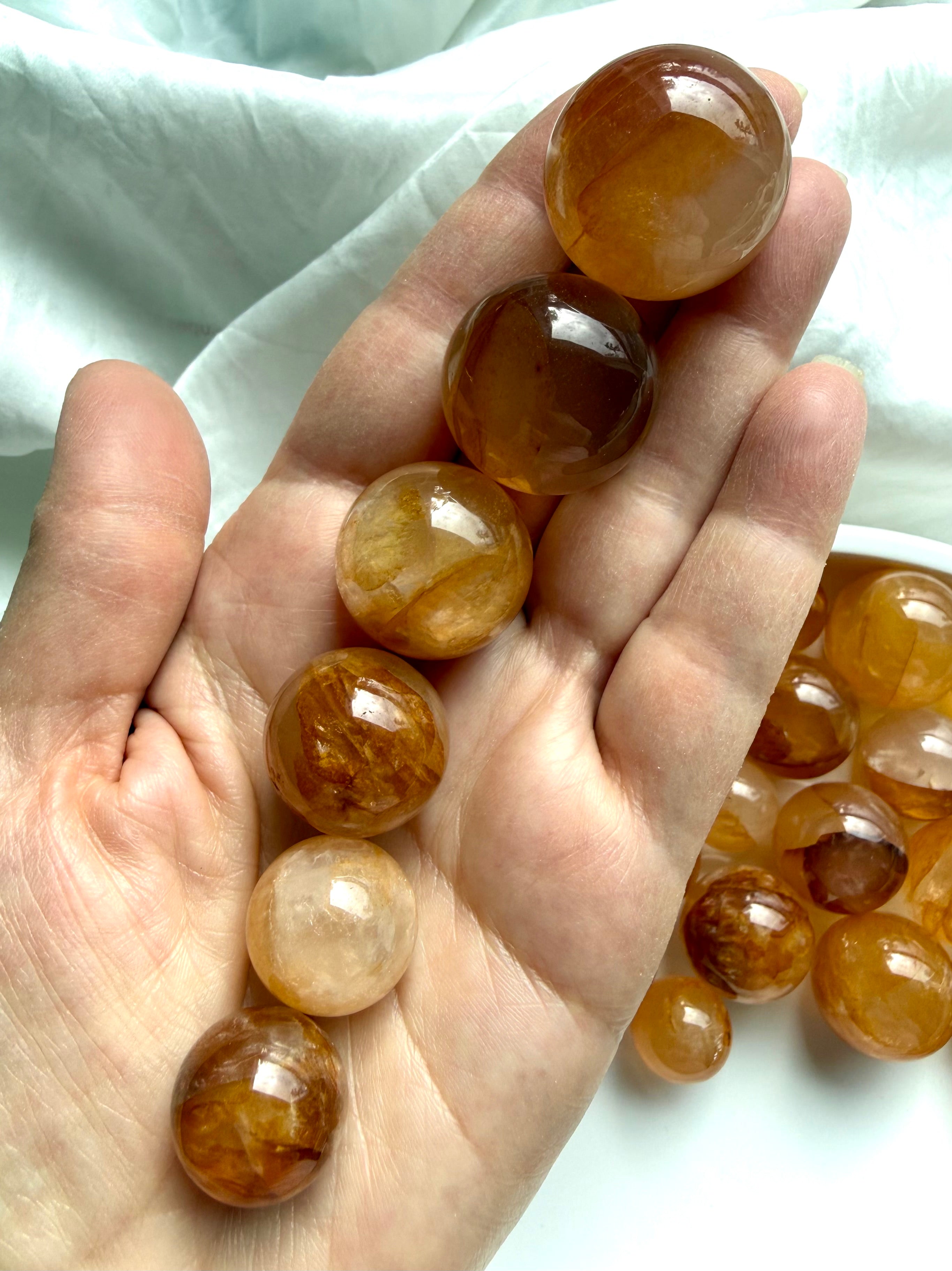 golden healer quartz mini spheres in hand showing variation in tone clarity and inclusions