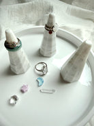 Faceted white and gray marble ring holder stand styled with stacked rings on modern jewelry display