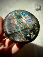 Rainbow Labradorite palm stone showing electric blue, gold and aqua flash with subtle violet tones in angled light