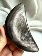 Silver Sheen Obsidian crescent moon crystal held in hand, polished obsidian for protection, insight, and grounding energy