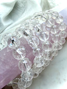 Rainbow Clear Quartz bracelet displayed on pink rose quartz with luminous transparent crystal beads