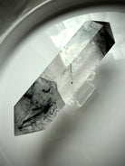 tourmalinated quartz DT crystal on white tray with soft natural lighting
