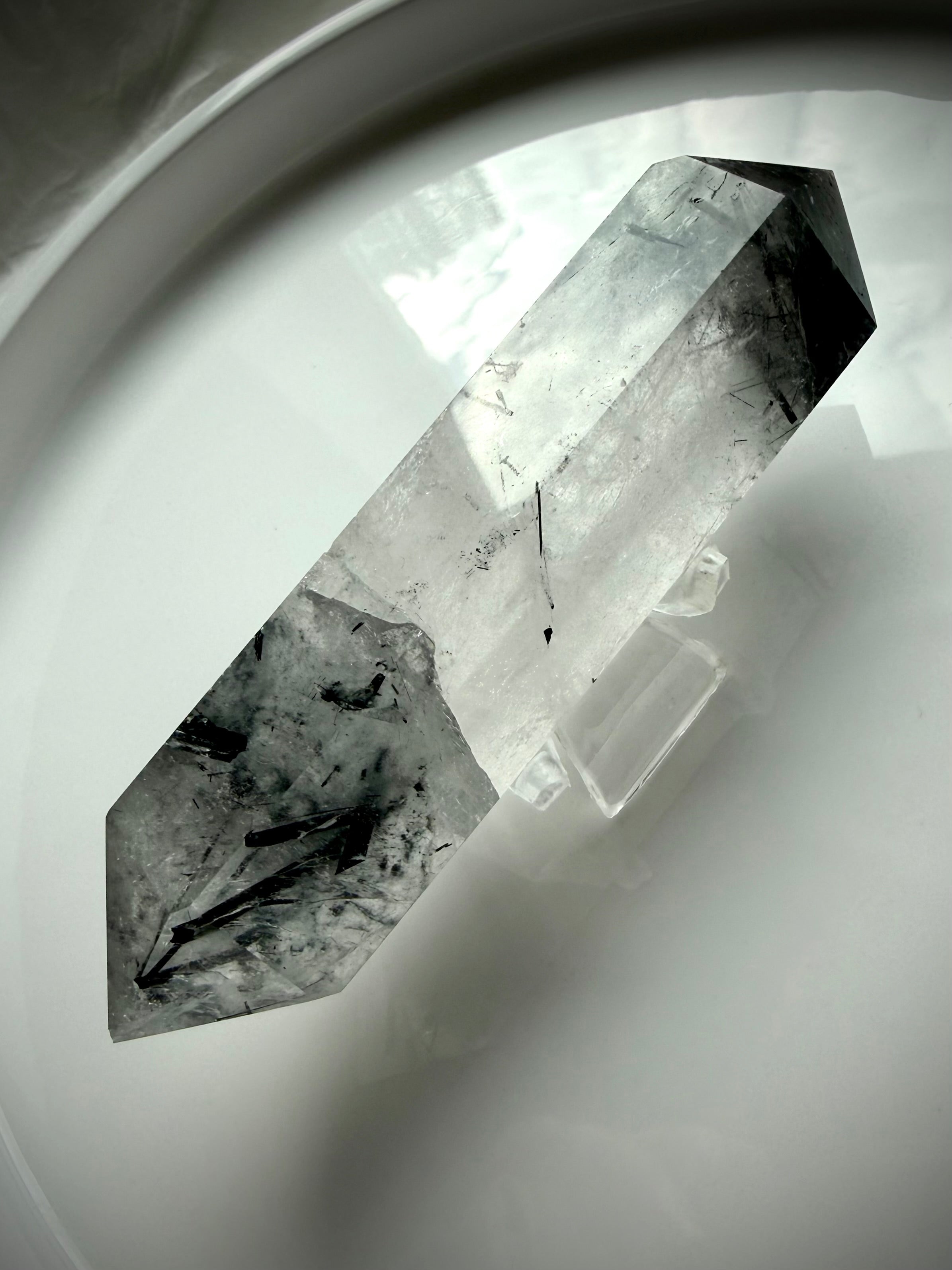 tourmalinated quartz DT crystal on white tray with soft natural lighting