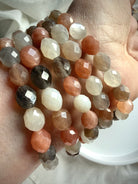 Multicolor Moonstone bracelet with faceted oval beads stacked on a wrist, featuring peach, gray, champagne, and white tones 
