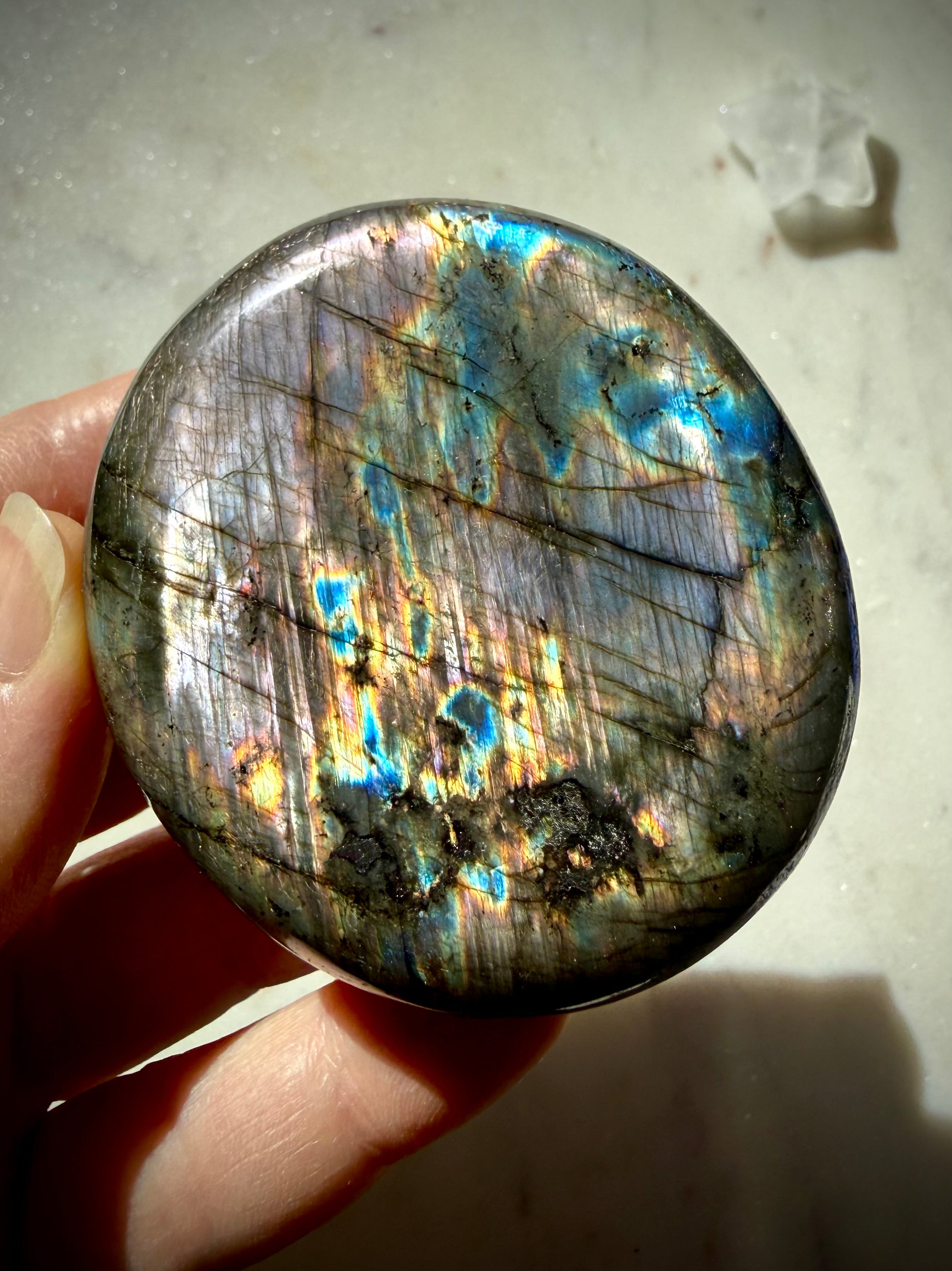 Labradorite palm stone with vivid blue, aqua and gold labradorescence shifting across natural silver flash matrix