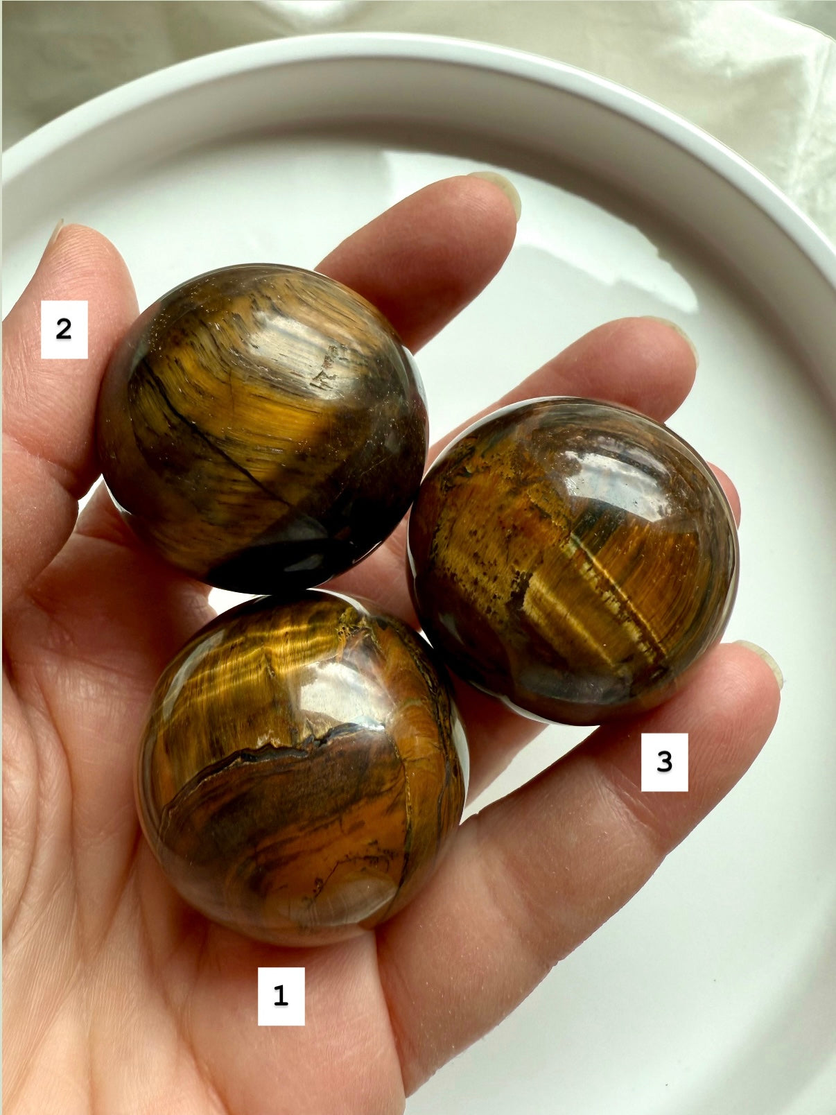 Three Tiger’s Eye spheres in hand: protective crystals for spiritual strength &amp; grounded energy flow