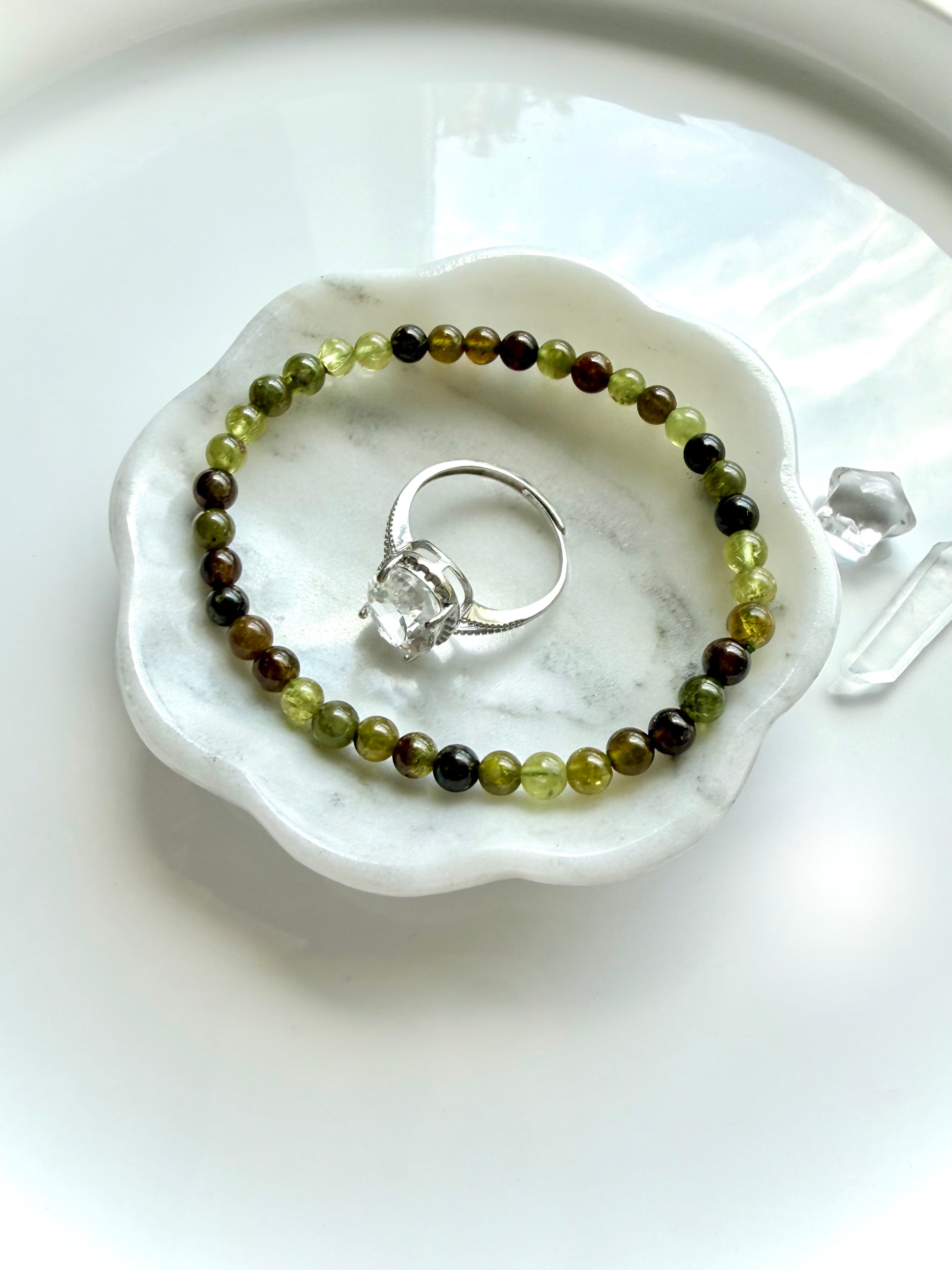 Tsavorite Garnet crystal bracelet shown with a gemstone ring in a marble jewelry dish, vanity table styling