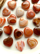 Overhead view of Mini Carnelian Hearts with unique patterns, Sacral Chakra crystals for motivation and inspired action