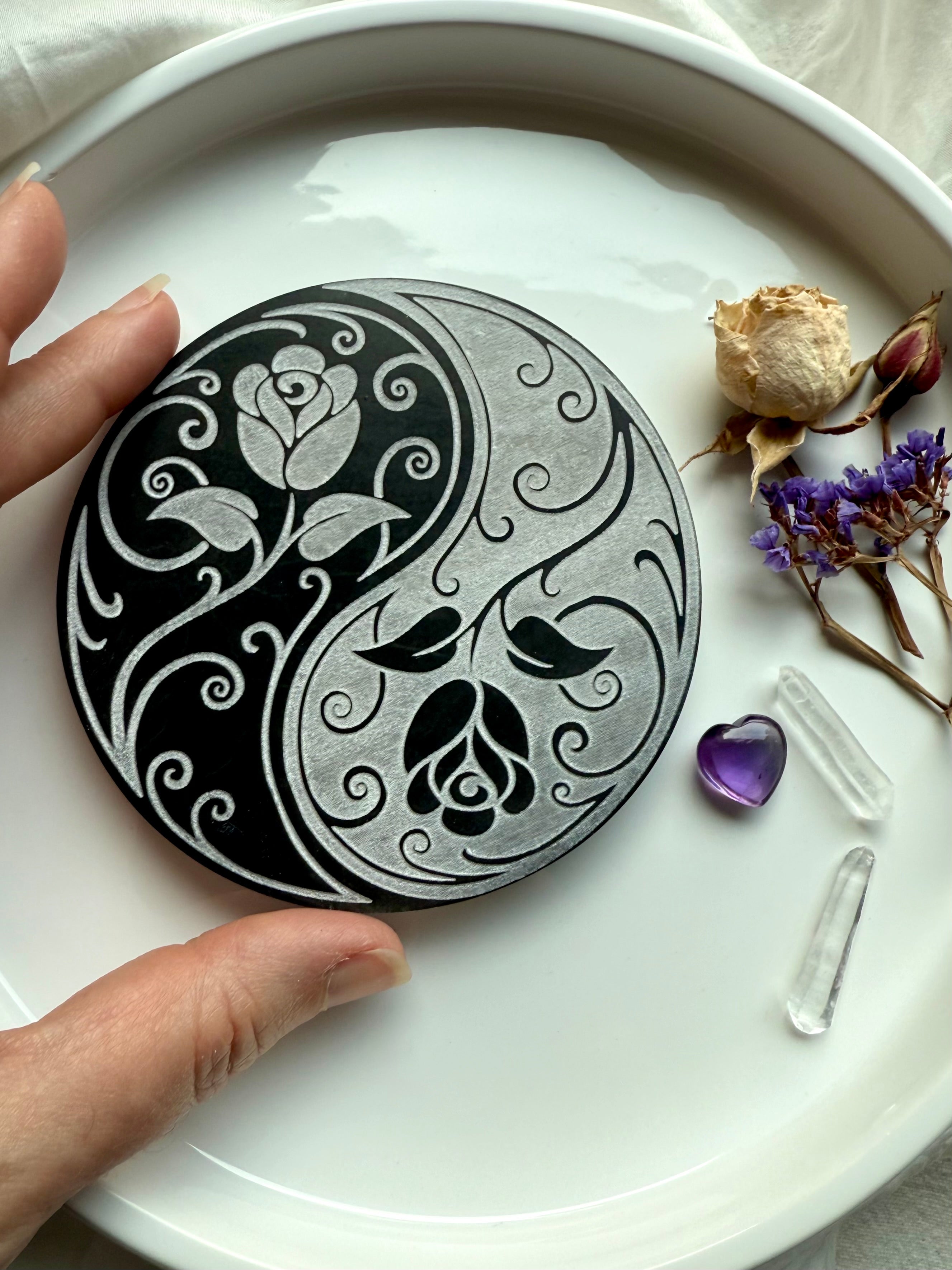 Yin yang rose selenite plate surrounded by dried flowers, amethyst, and clear quartz points for energy rituals