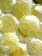 Close-up of lemon calcite palm stones with a mix of milky and crystalline patterns