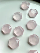 Zoom in on several faceted rose quartz hexagons, showing translucent pink color and natural veining, mini crystals for love and emotional healing