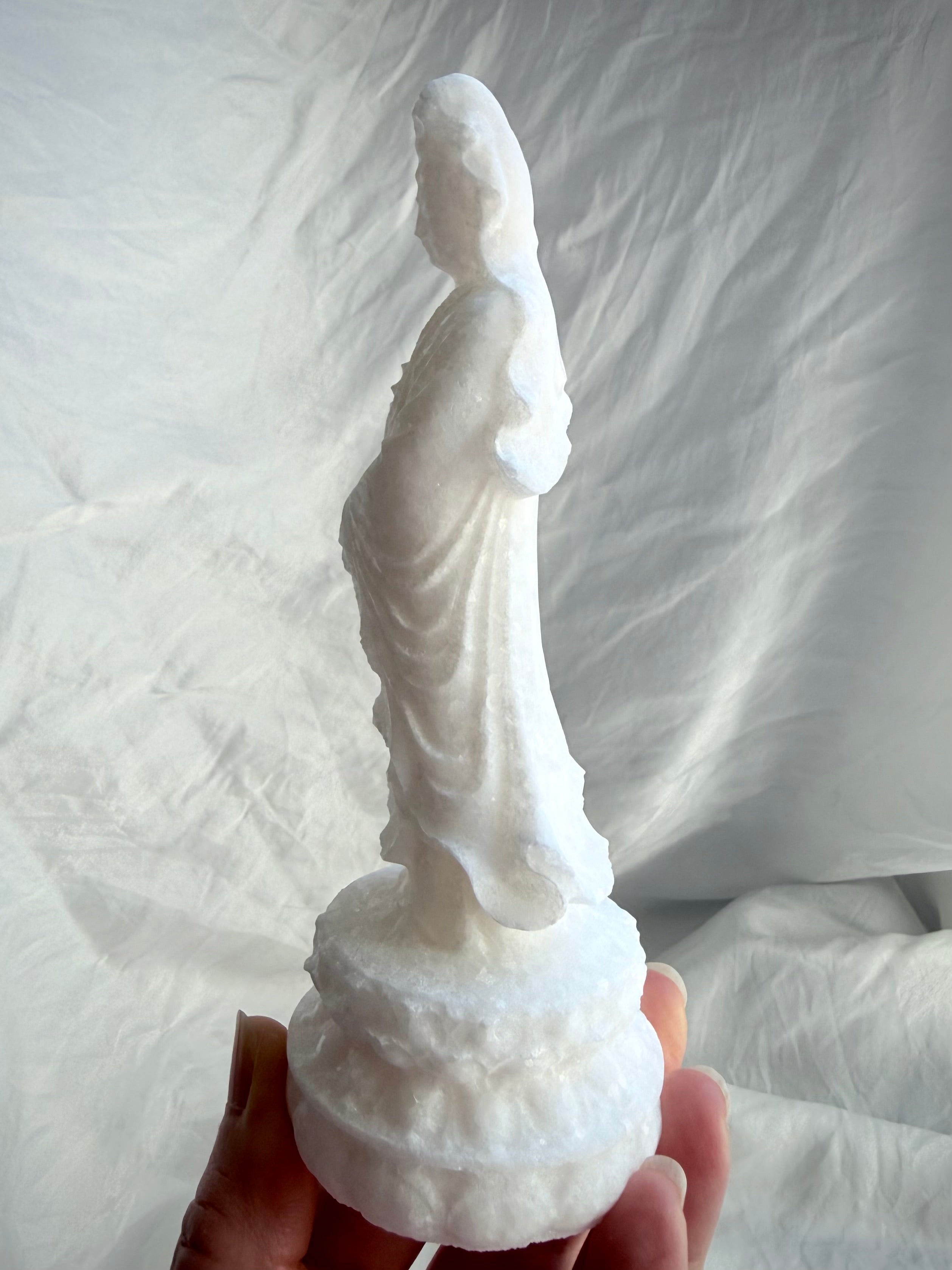 White Jade Standing Quan Yin statue held in hand from the side, showing flowing robes and natural crystalline sparkle