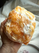 Handheld Orange Calcite crystal from Mexico with raw yet refined texture and glowing interior color
