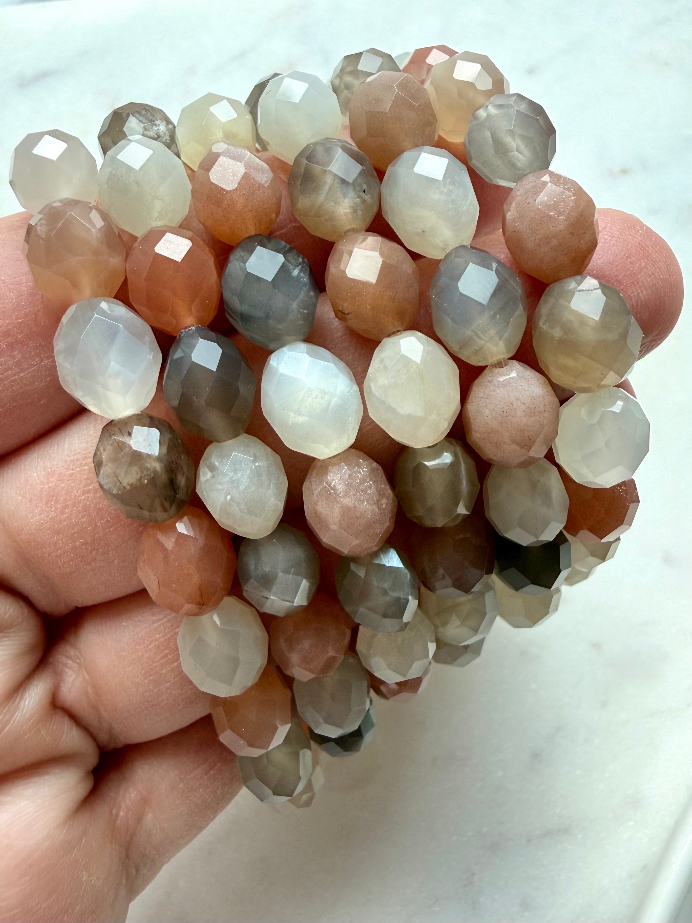 Multicolor Faceted Moonstone crystal bracelets with translucent peach, gray, and white gemstone beads displayed in hand