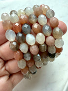 Multicolor Faceted Moonstone crystal bracelets with translucent peach, gray, and white gemstone beads displayed in hand