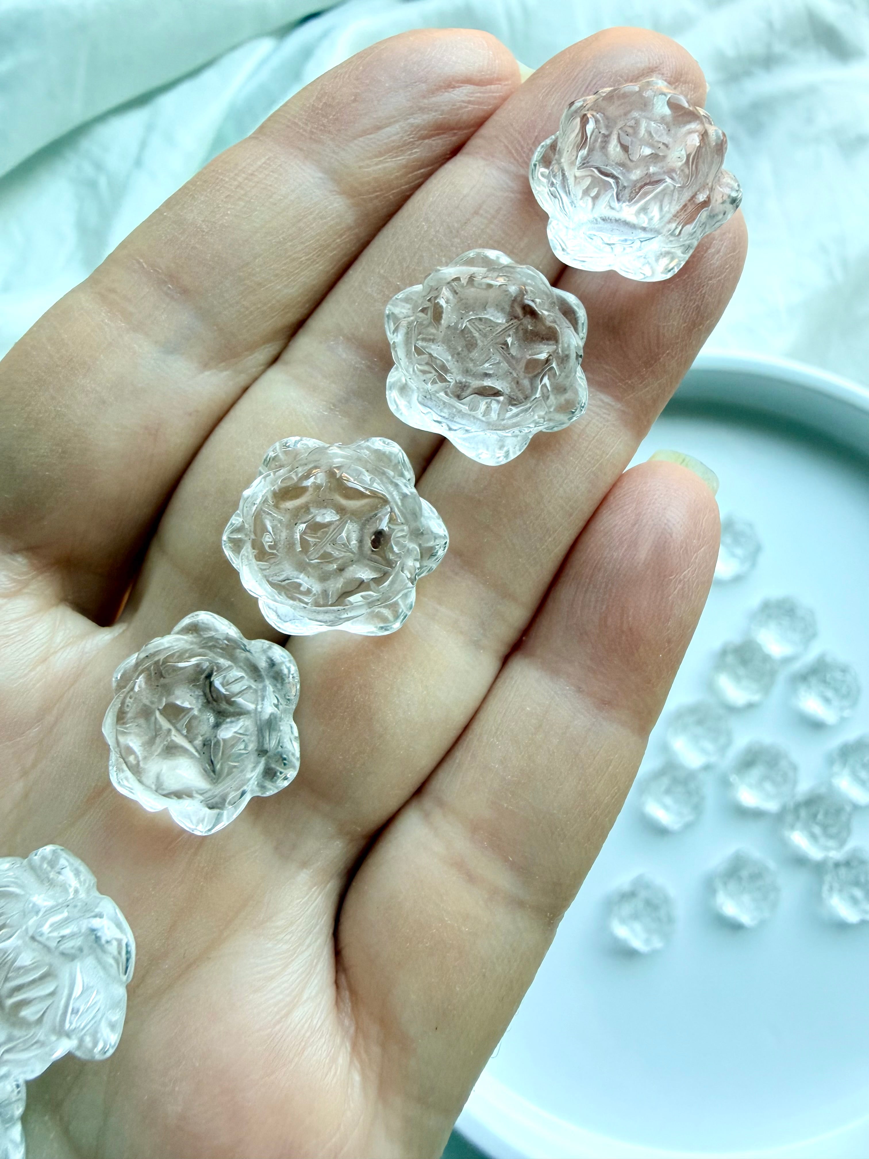 Closeup of mini Clear Quartz lotus flower crystals held in hand, tiny polished carvings for pocket stones, crystal grids and gifts