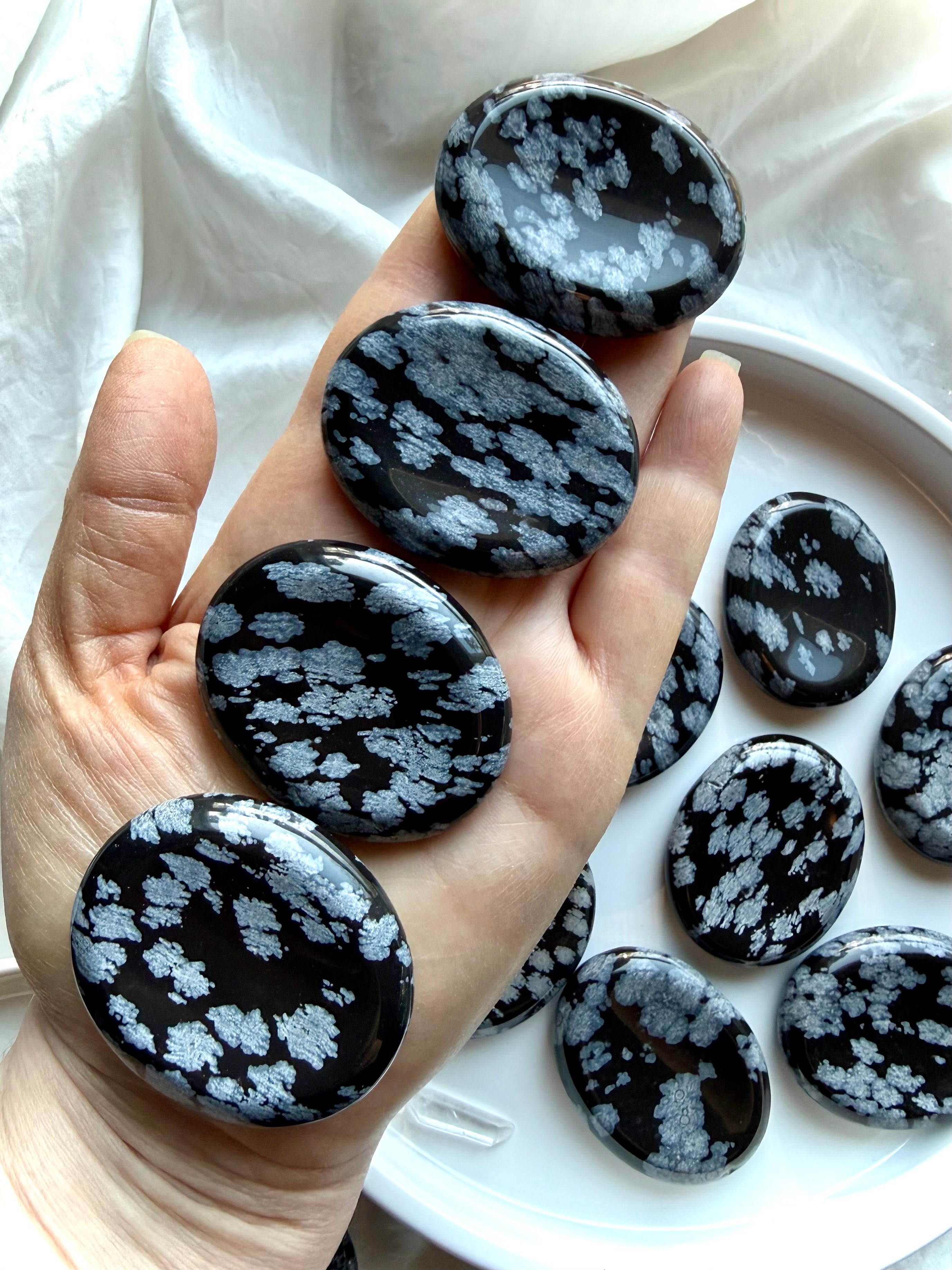 Snowflake Obsidian worry stones held in hand for scale, grounding, and anxiety relief