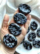 Snowflake Obsidian worry stones held in hand for scale, grounding, and anxiety relief