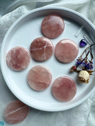 Six polished Rose Calcite discs displayed in a white ceramic dish with healing crystals and dried rose and statice flowers