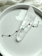 Aquamarine gemstone bracelet with silver butterfly charms displayed across a clear quartz point for spiritual healing and clarity