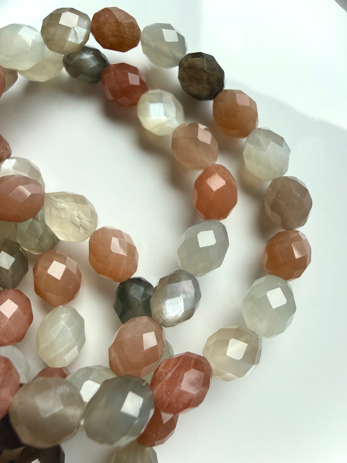 Close-up of natural Faceted Moonstone bracelets showing peach and gray gemstones, silky shimmer, and occasional needle-like inclusions