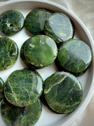 Polished nephrite jade palm stones with rich green tones and mineral inclusions, smooth round meditation crystals for grounding and stability