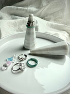 White and gray marble ring holder with faceted sculptural design on vanity display