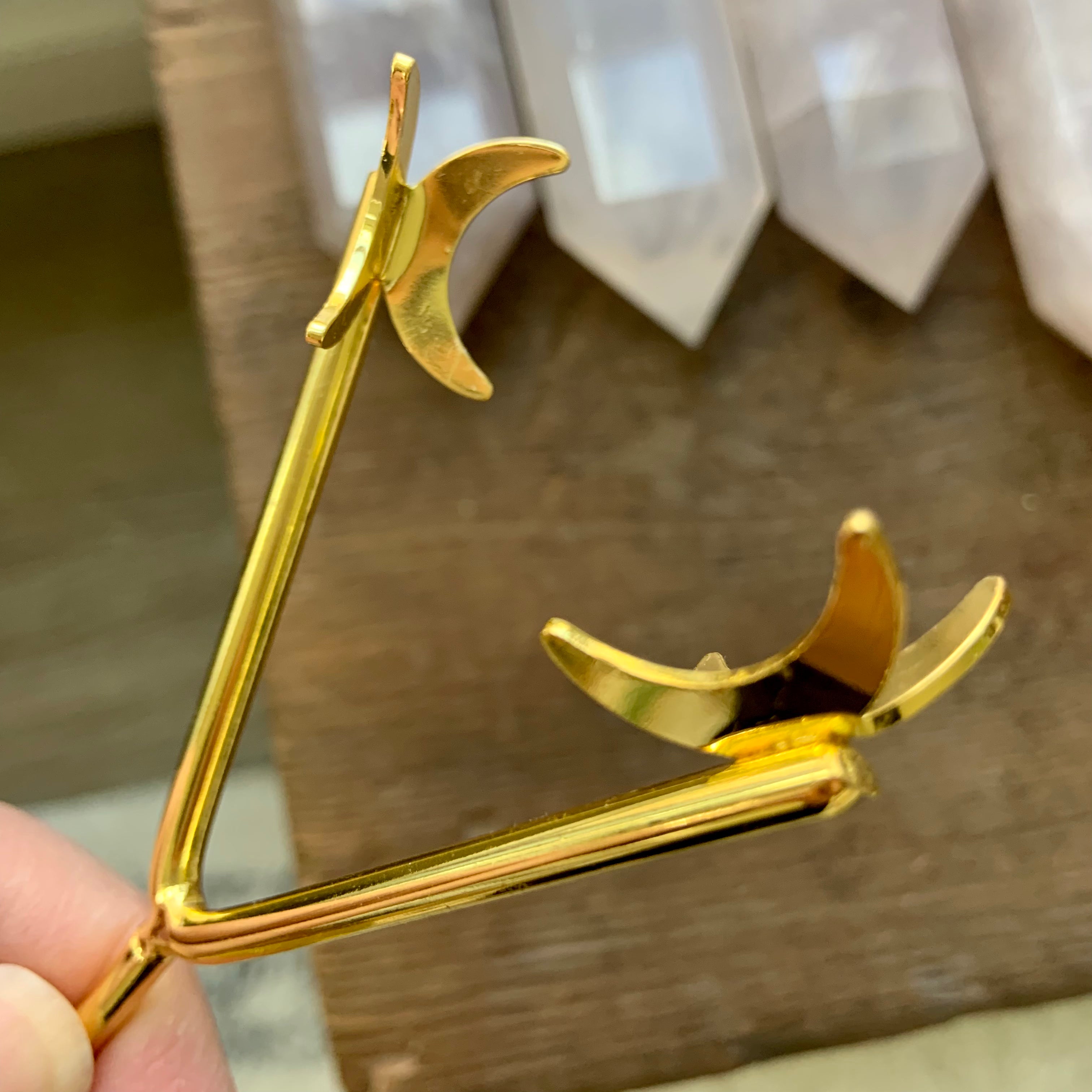 Close-up of gold crystal holder prongs shaped like crescent moons — secure and stylish display for hearts, palms & crystals.