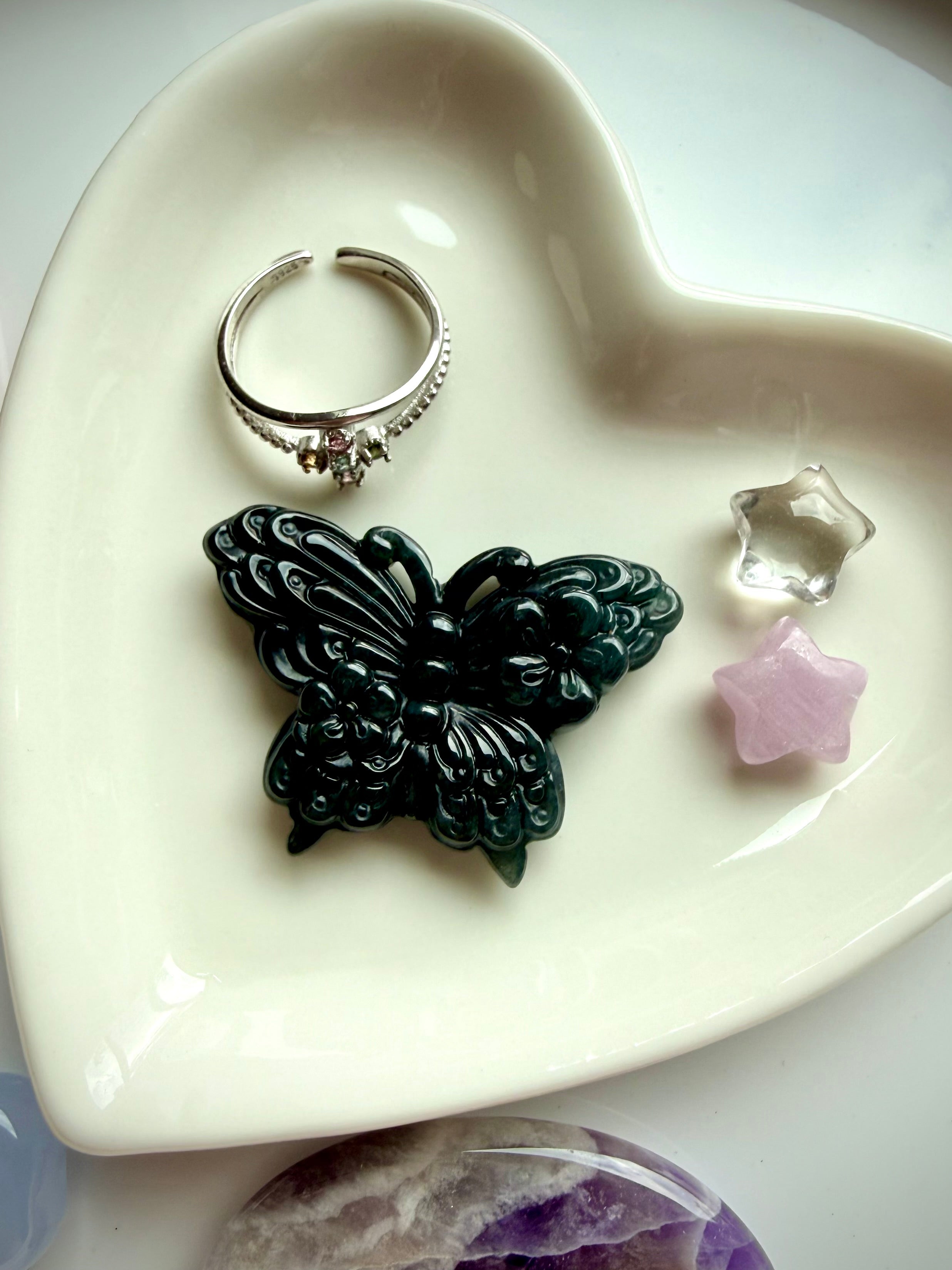 Wuji jade butterfly carving on vanity tray with crystal jewelry and gemstones showing natural Guatemalan jade butterfly