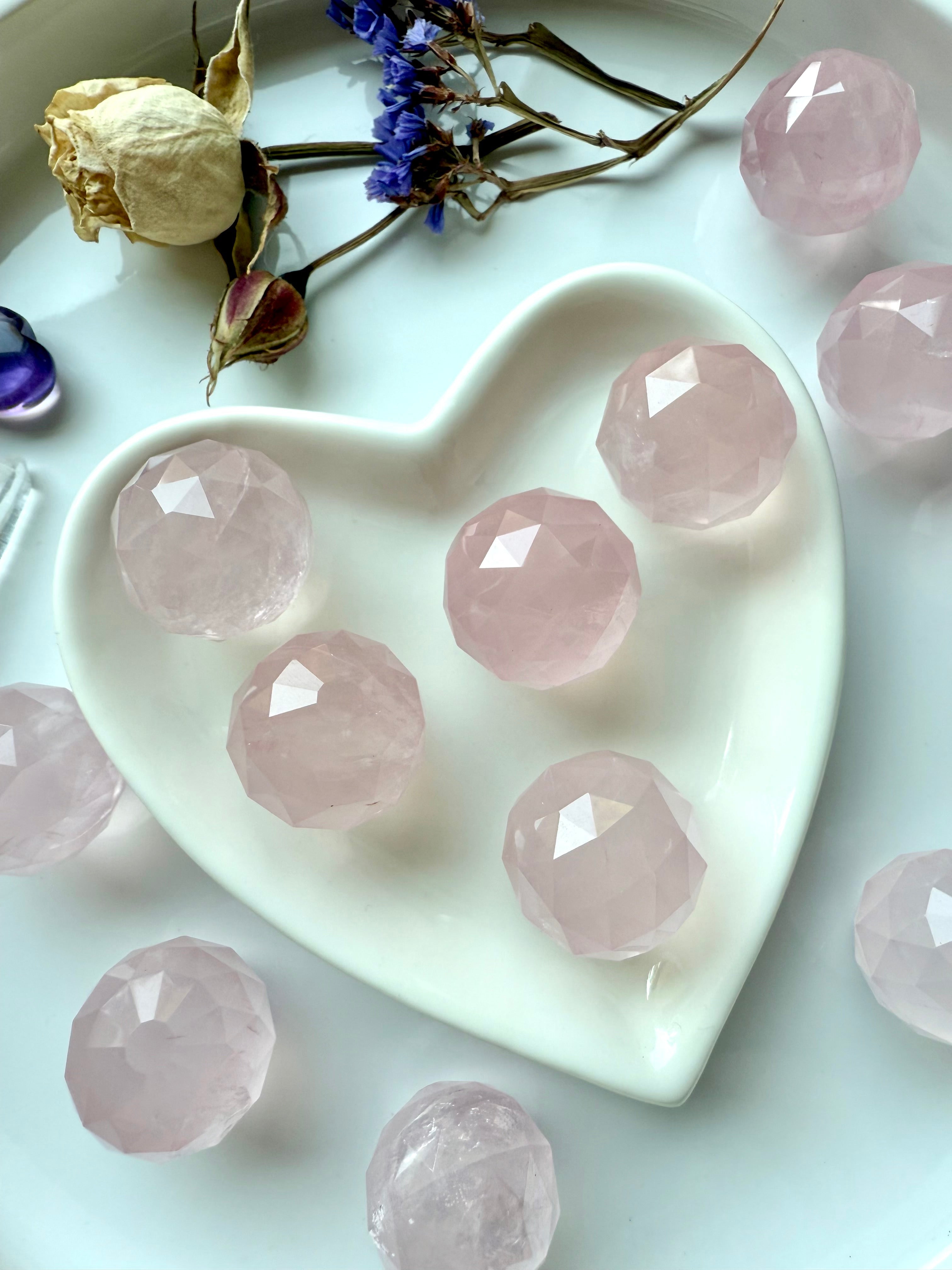 Close up of a heart-shaped dish filled with small rose quartz crystal balls for heart chakra healing.