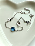 Aquamarine butterfly bracelet with dainty sterling silver chain styled in a heart-shaped dish — March birthstone jewelry for peace, clarity, and throat chakra healing