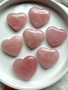Rose Quartz heart crystals arranged on a white dish showing soft blush pink color and natural translucence