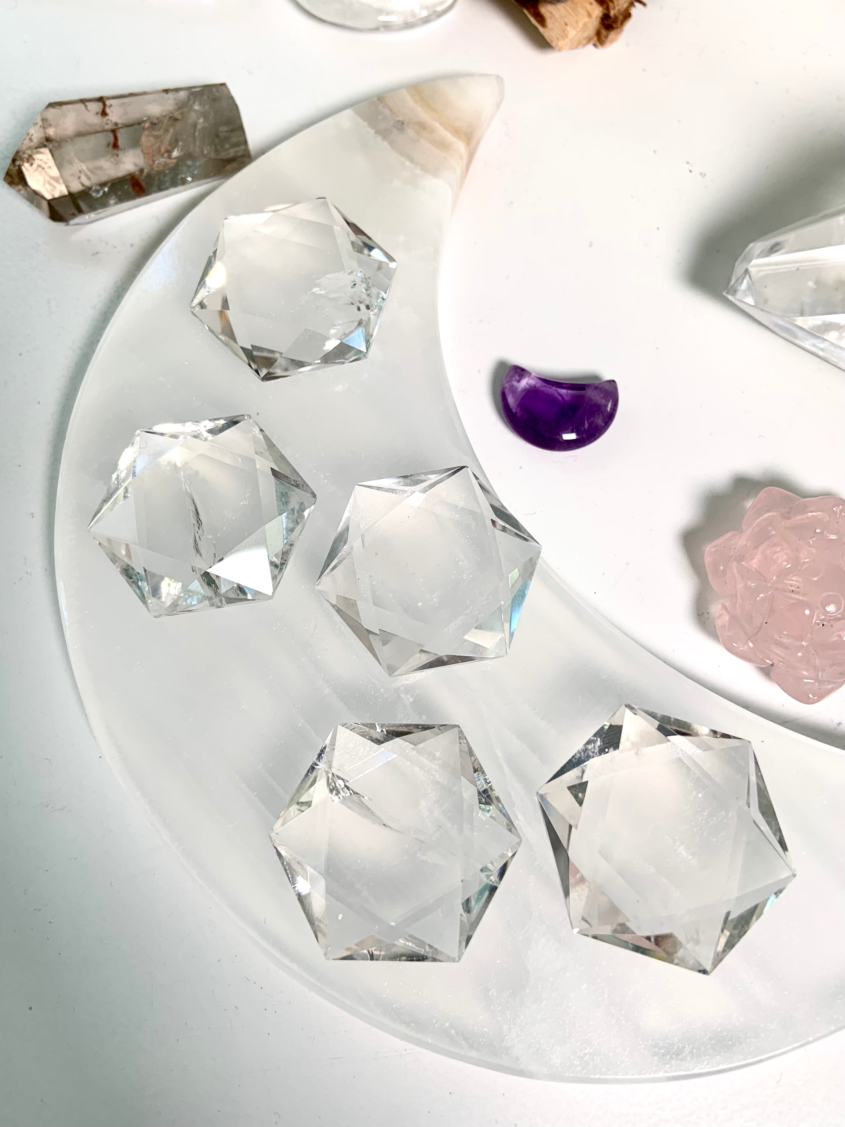 Overhead view of large Clear Quartz hexagons arranged on white moon plate with surrounding crystals