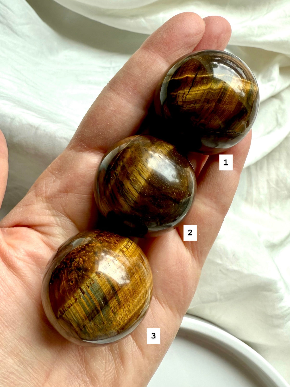 Tiger’s Eye spheres in hand, displaying silky bands &amp; chatoyancy: stones for courage, focus, &amp; energy alignment