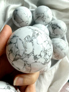 Howlite crystal ball close view in hand with intricate gray web-like veining, meditation stone for anxiety relief and mental clarity