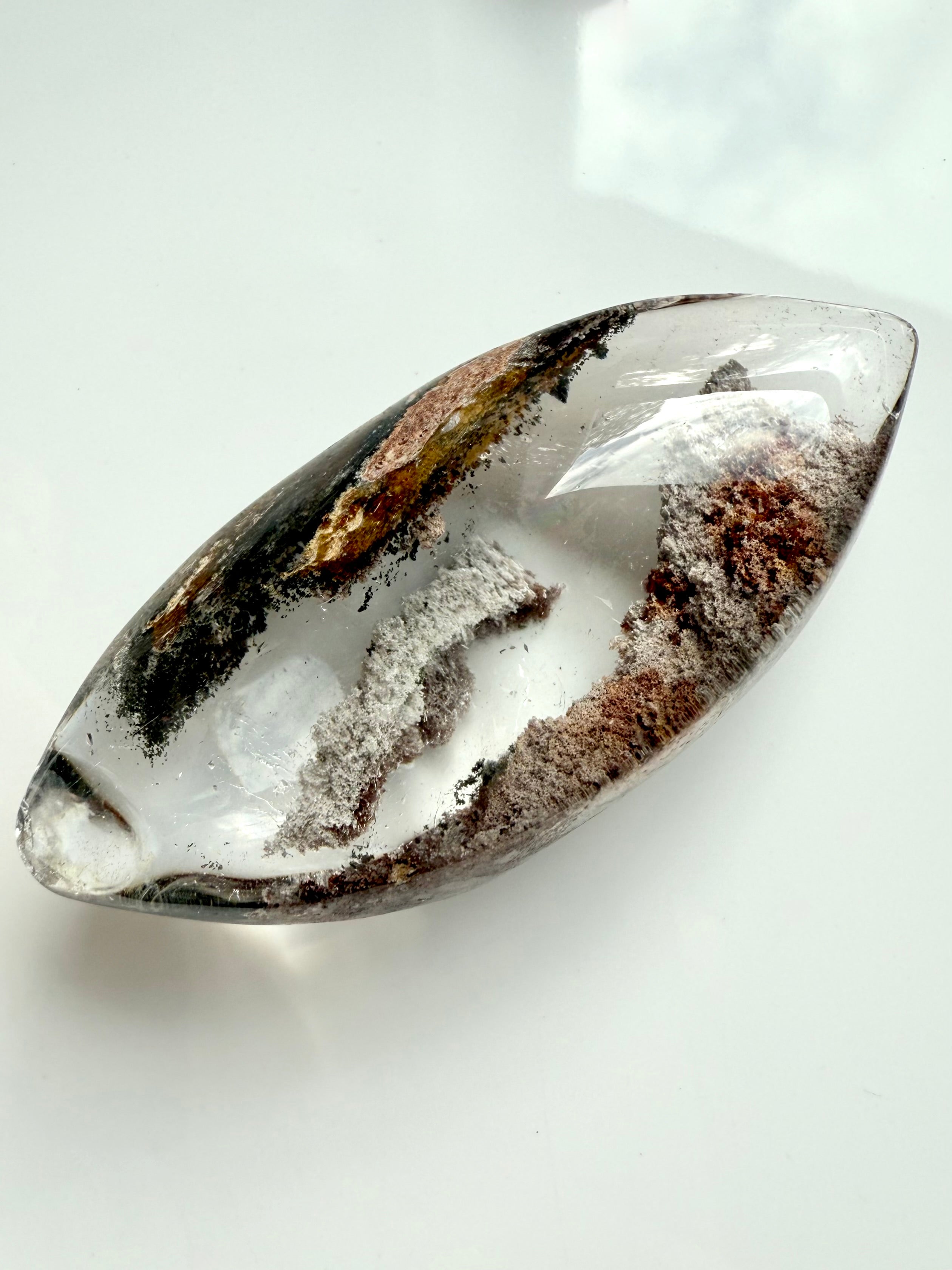 Polished Garden Quartz lens showing layered phantom lines and scenic lodolite inclusions