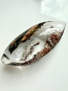 Polished Garden Quartz lens showing layered phantom lines and scenic lodolite inclusions
