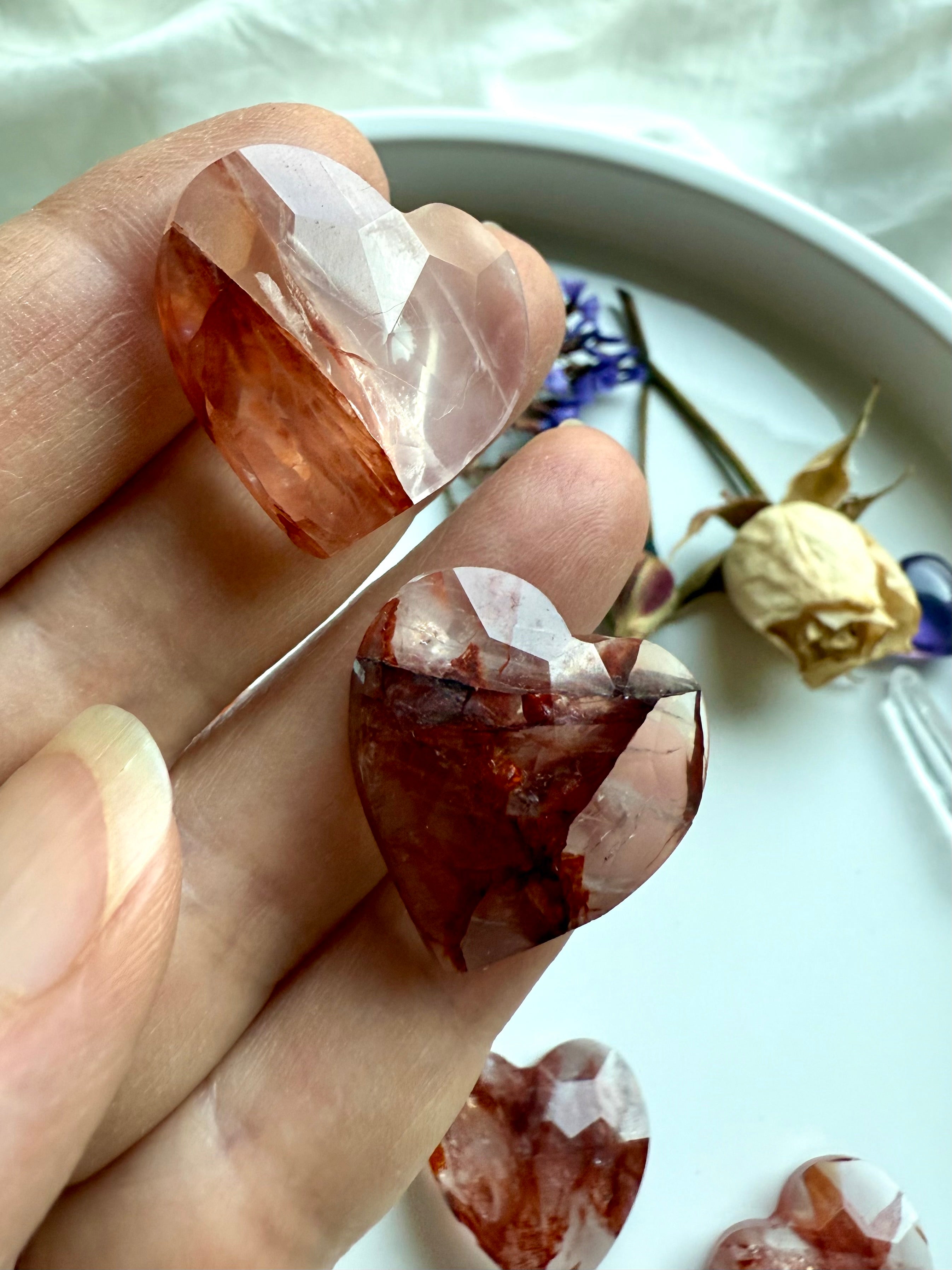 Closeup of two faceted Fire Quartz hearts – small crystal carving for energy and grounding
