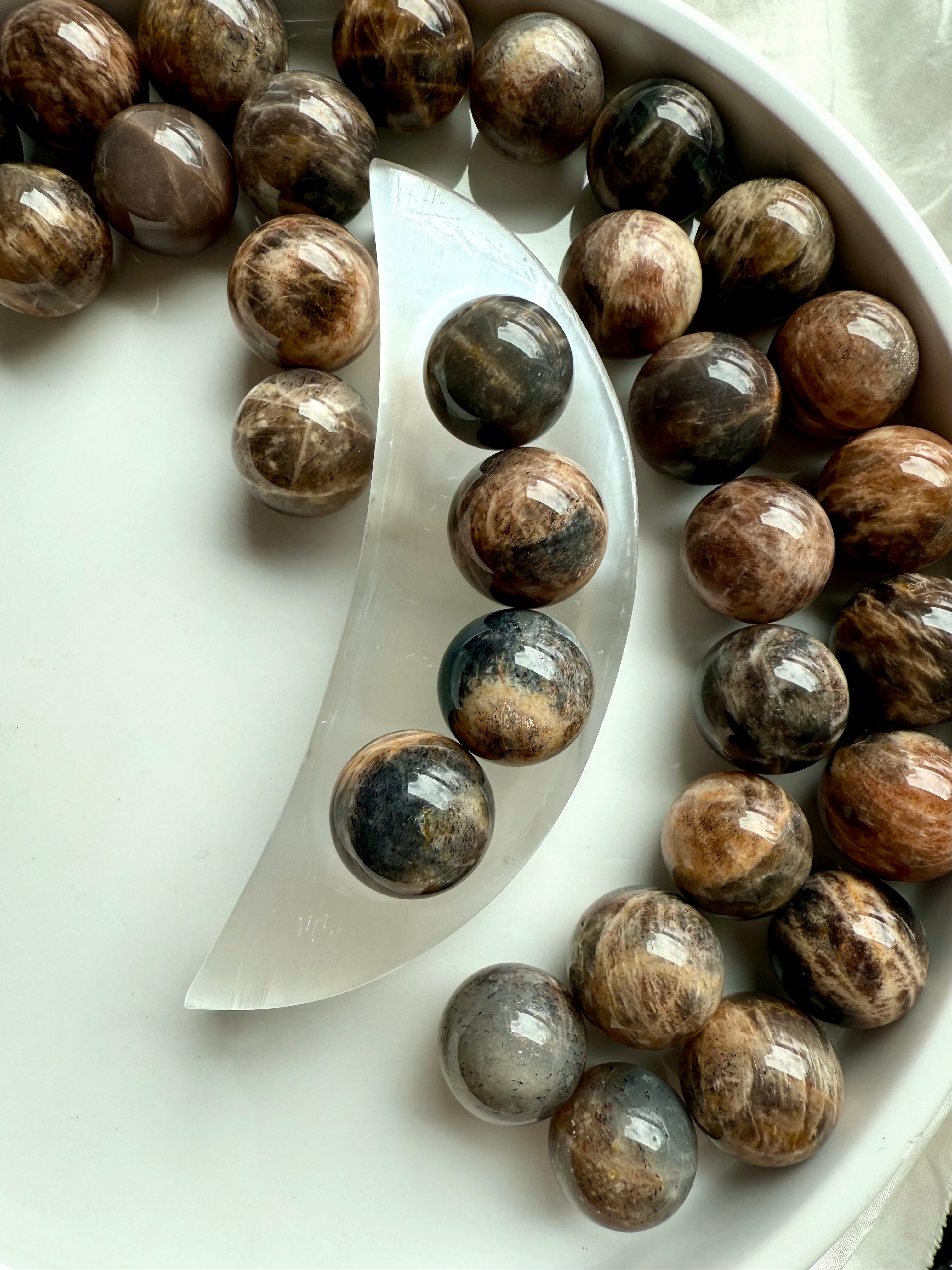 Mini Black Moonstone spheres in a selenite moon bowl, surrounded by more spheres — crystals for intuition, grounding & feminine energy