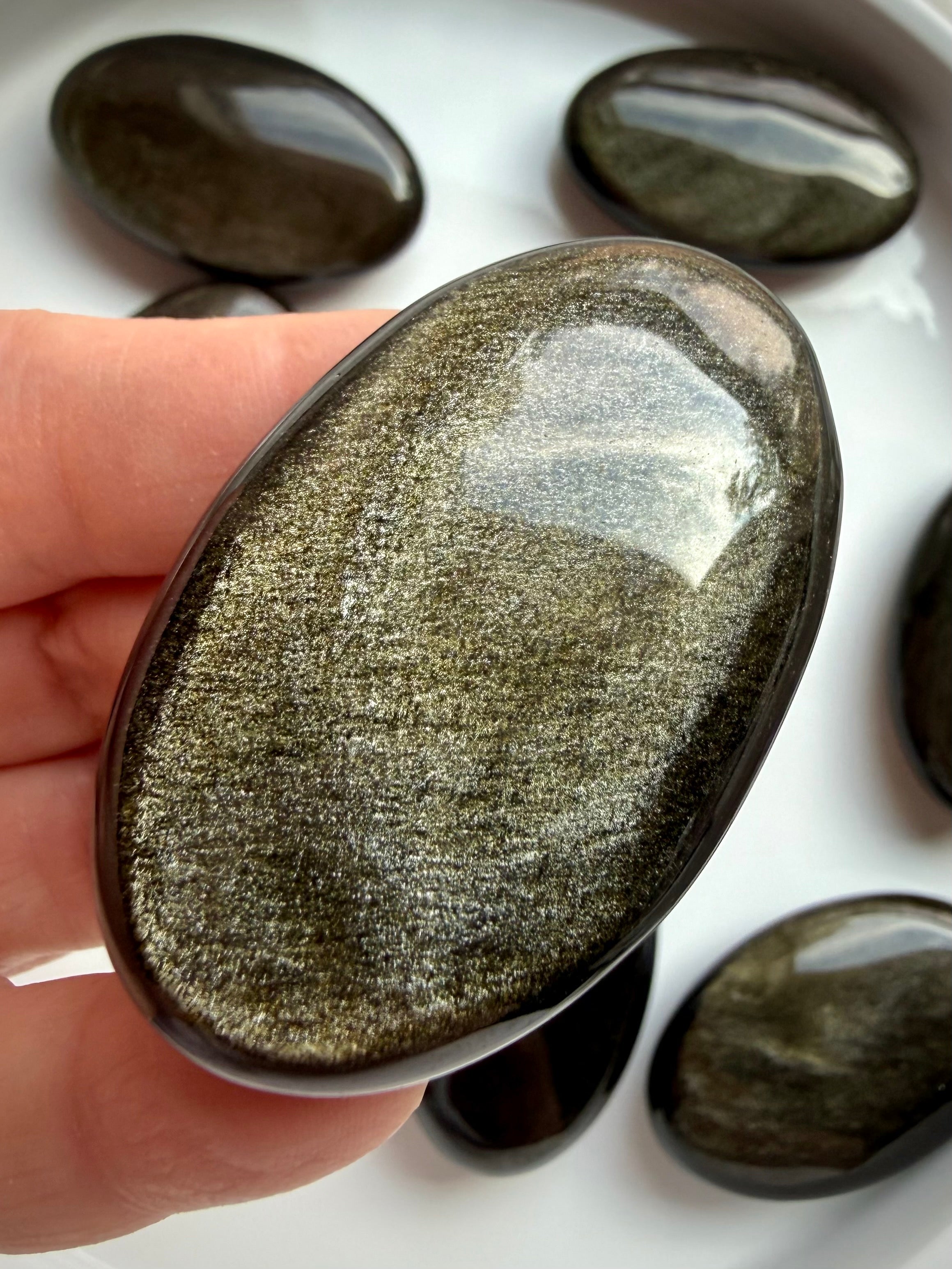 Golden Sheen Obsidian palm stone held in hand showing brilliant golden shimmer across its polished black surface