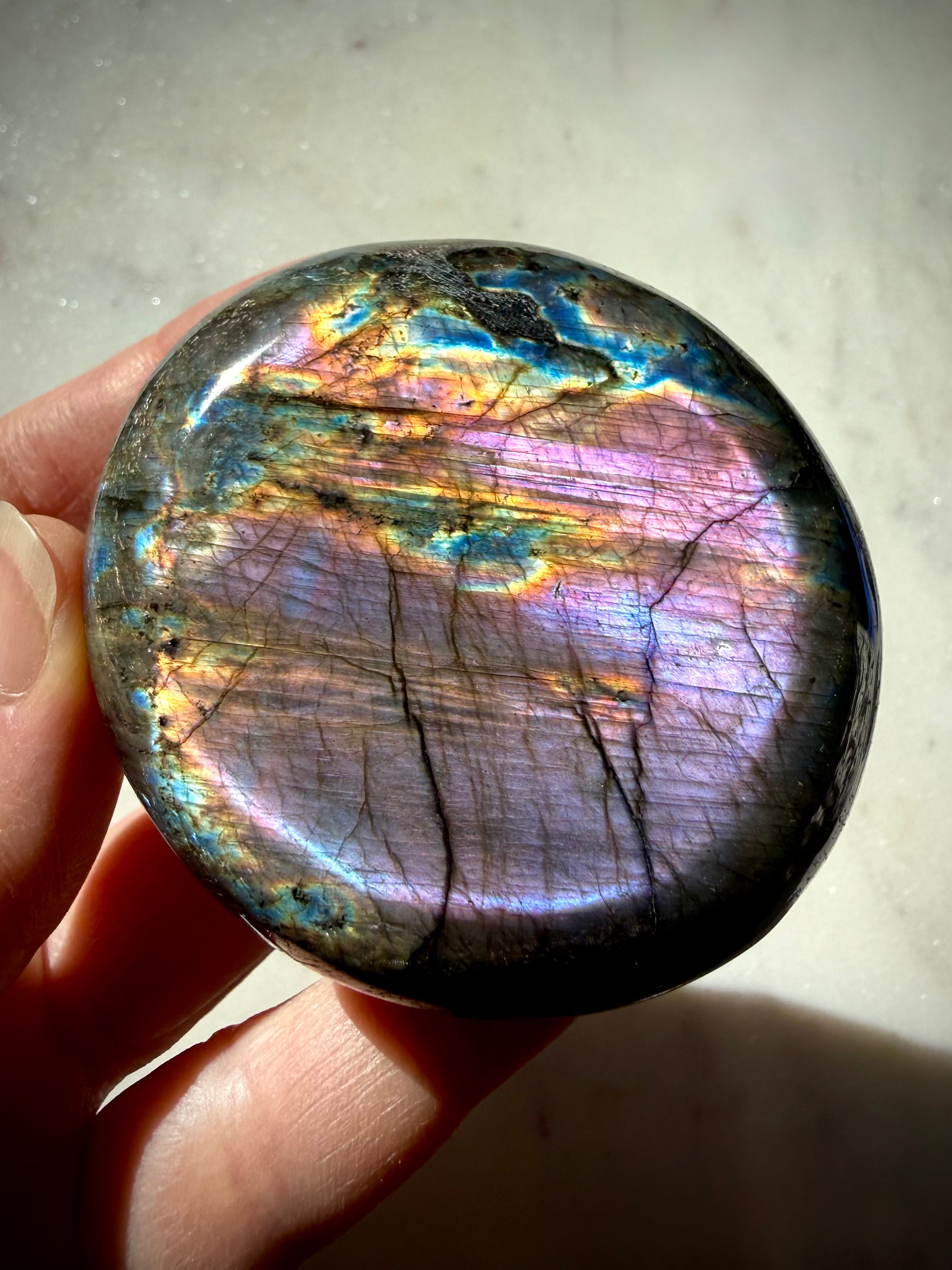 Violet Labradorite crystal held in hand with purple, blue and warm rainbow flash for intuition and Third Eye Chakra energy