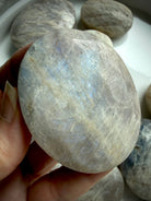 high flash belomorite moonstone palm stone with blue shimmer and natural mineral inclusions